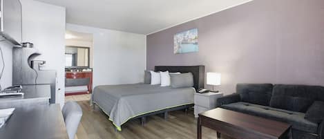 A hotel room with a bed, a desk, a sofa, and a dining table.