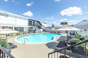 A swimming pool with lounge chairs and umbrellas, a building with a staircase, and a satellite dish. - R Nite Star Hotel (Arlington)