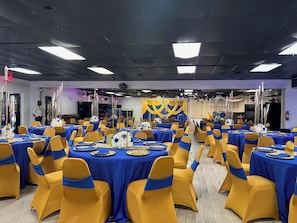 A banquet hall with tables set for a formal event, featuring blue tablecloths and yellow chairs. - R Nite Star Hotel (Arlington)