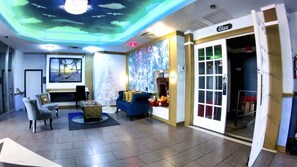 A hotel lobby with a modern design, featuring a blue sofa, a small table, and a decorative mirror.