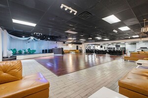 Amplo espaço interno com assentos de couro, palco decorado com balões e área de cozinha.