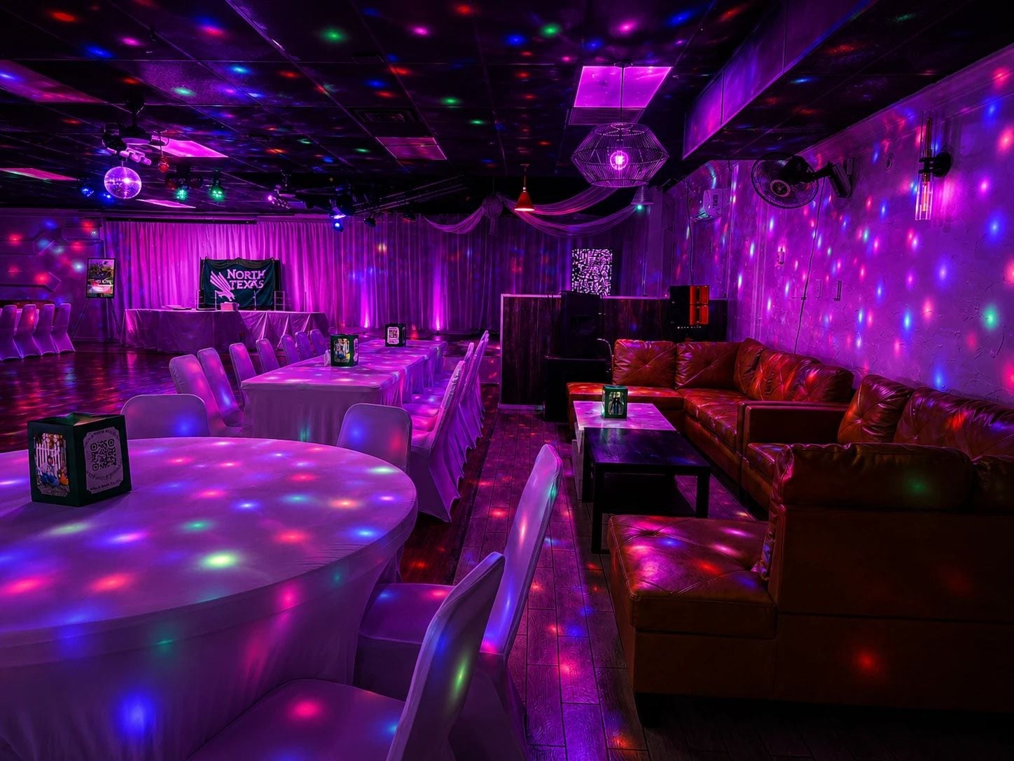 A room with tables and chairs, a sofa, and a disco ball.