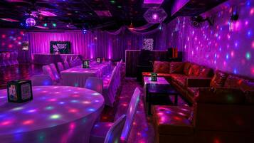 A room with tables and chairs, a sofa, and a disco ball.