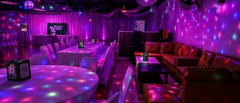Una habitación con mesas y sillas, un sofá y una bola de discoteca.