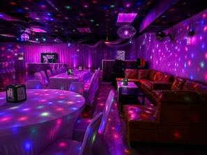 Een kamer met tafels, stoelen, een bank en een discobal.