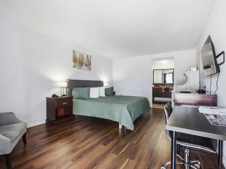 Een hotelkamer met een bed, een bureau, een stoel, een dressoir en een spiegel.