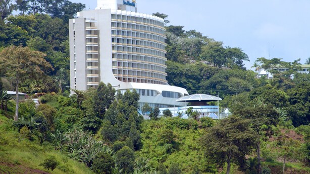 Ein modernes Hotel mit einer geschwungenen Fassade, umgeben von üppigem Grün.
