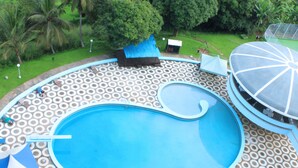 Ein Pool mit kreisförmigem Muster auf der Terrasse, umgeben von Grünpflanzen und einem überdachten Bereich mit Kuppeldach.