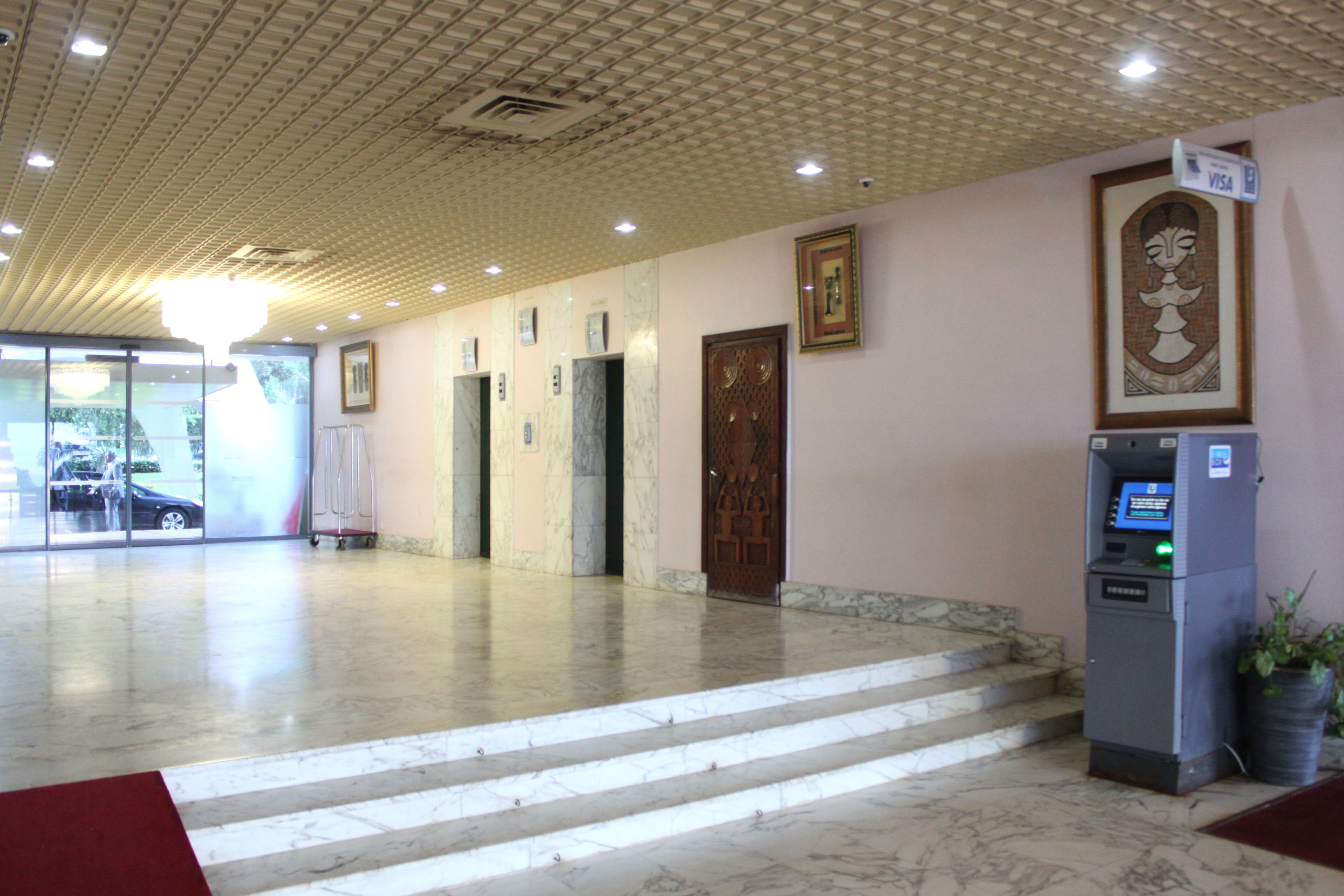A lobby with marble flooring, a reception desk, a cash machine, and a door with a decorative panel.