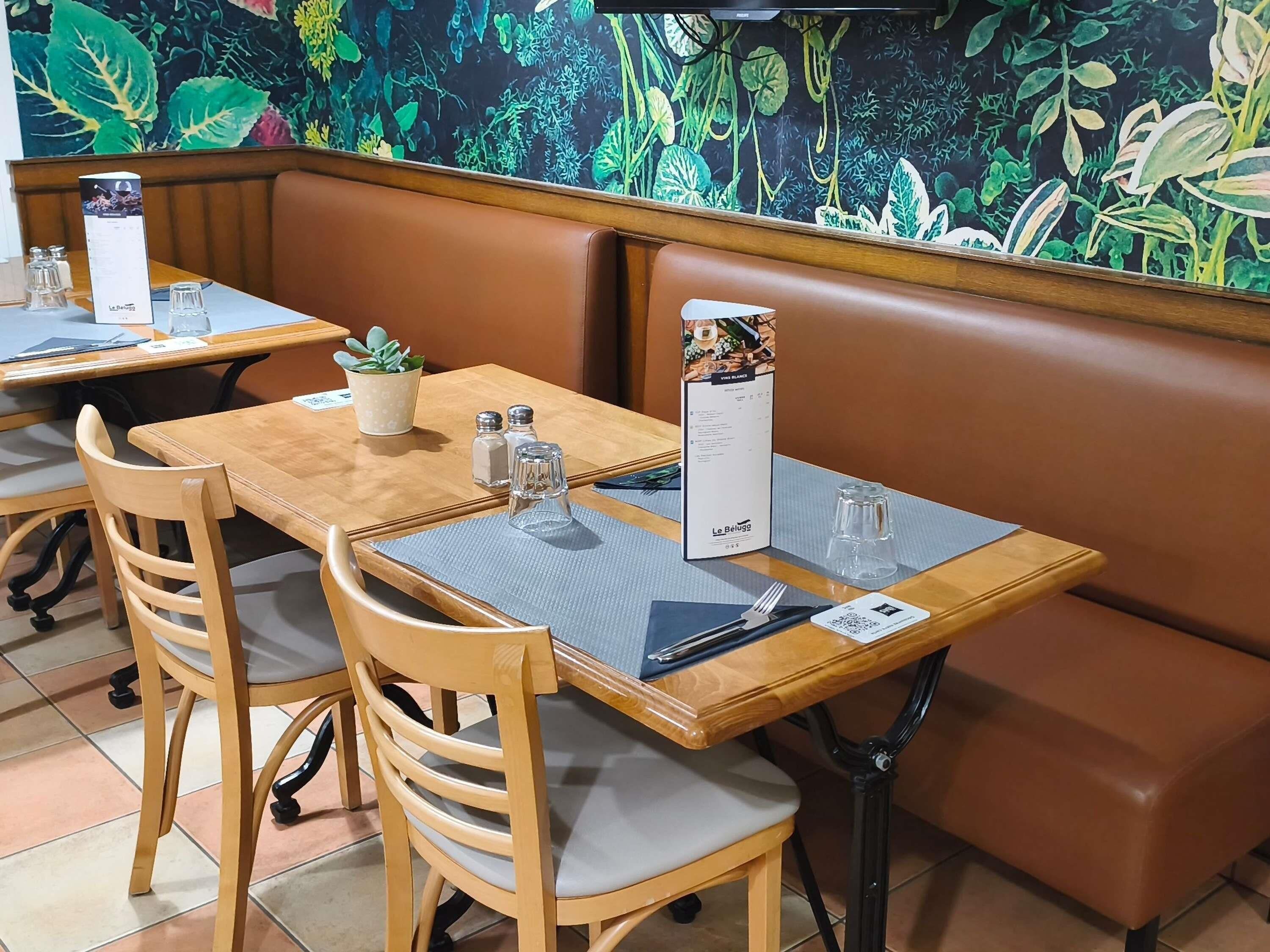 A restaurant with wooden tables and chairs, a menu stand, and a decorative wall.