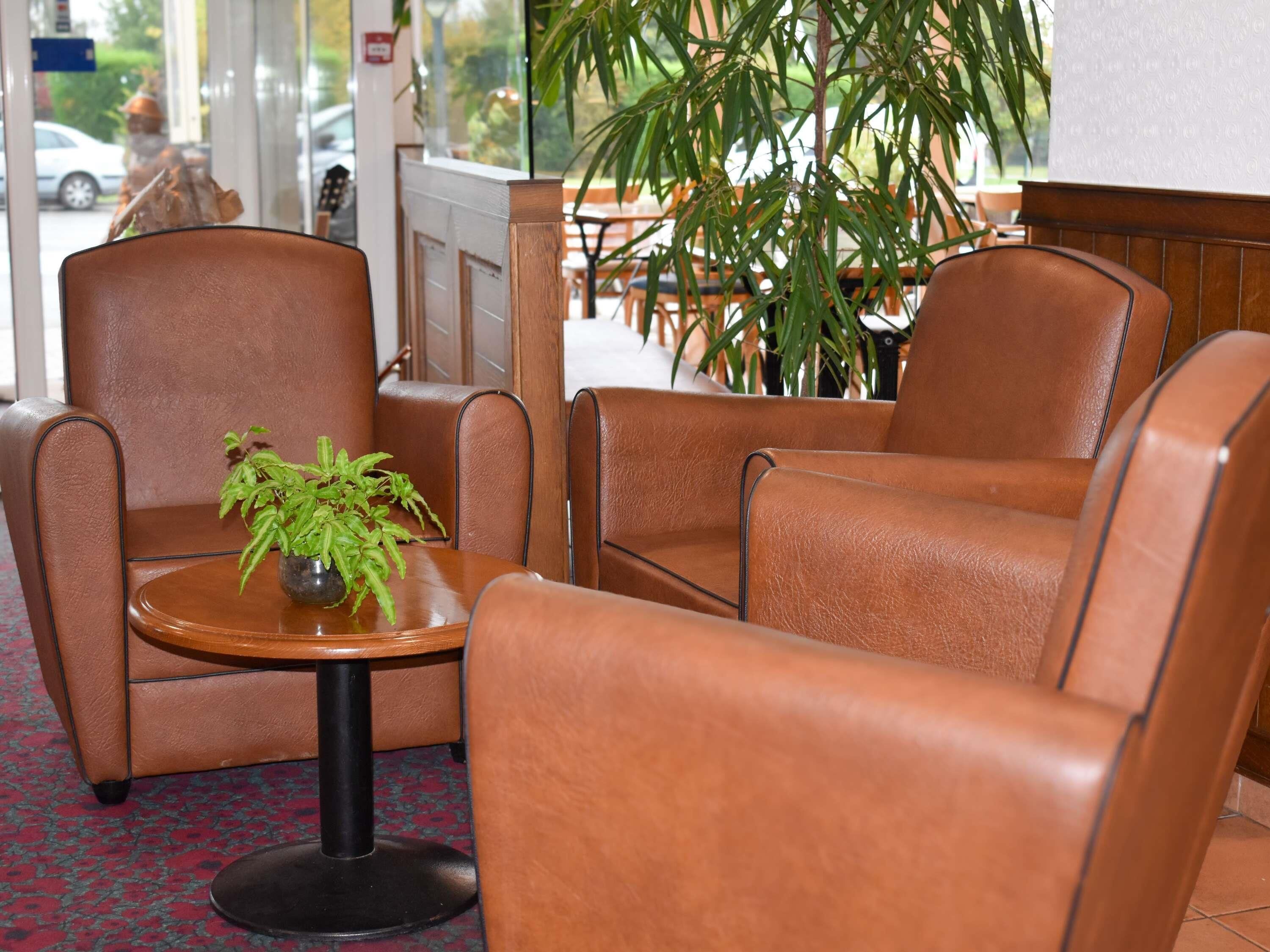 A seating area with leather chairs and a small table with a plant.