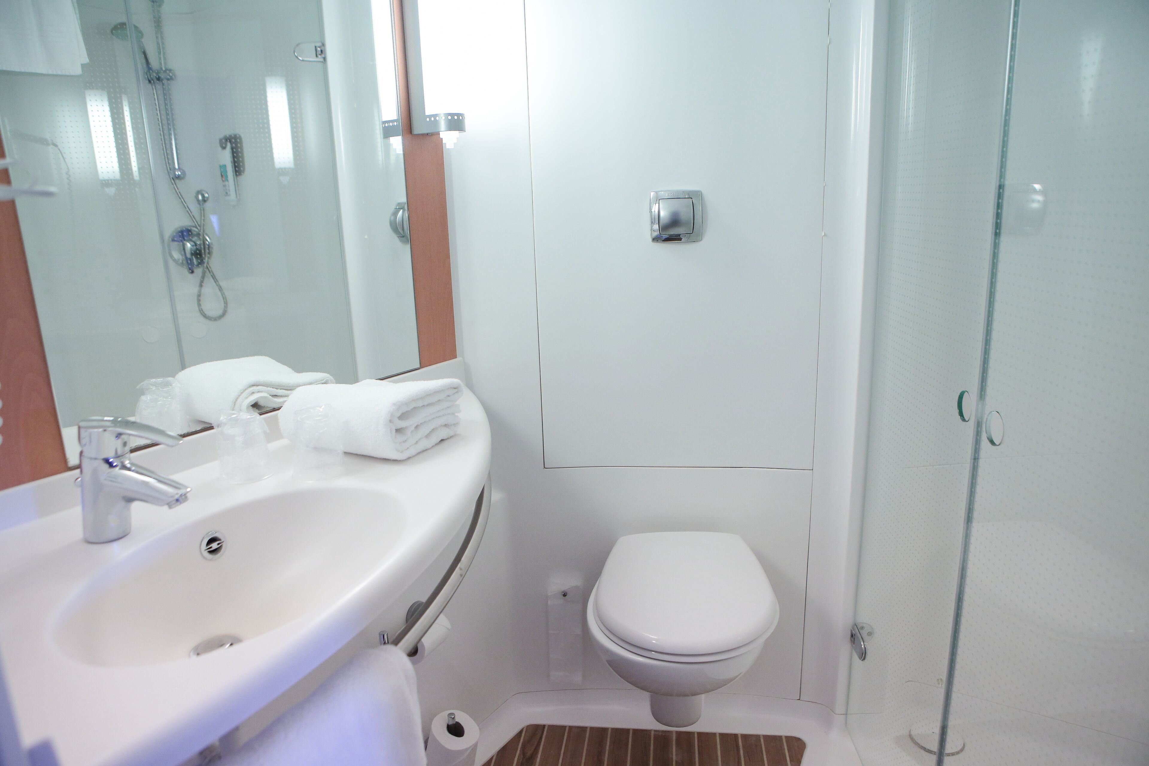 Een badkamer met een wastafel, spiegel, toilet en douche.