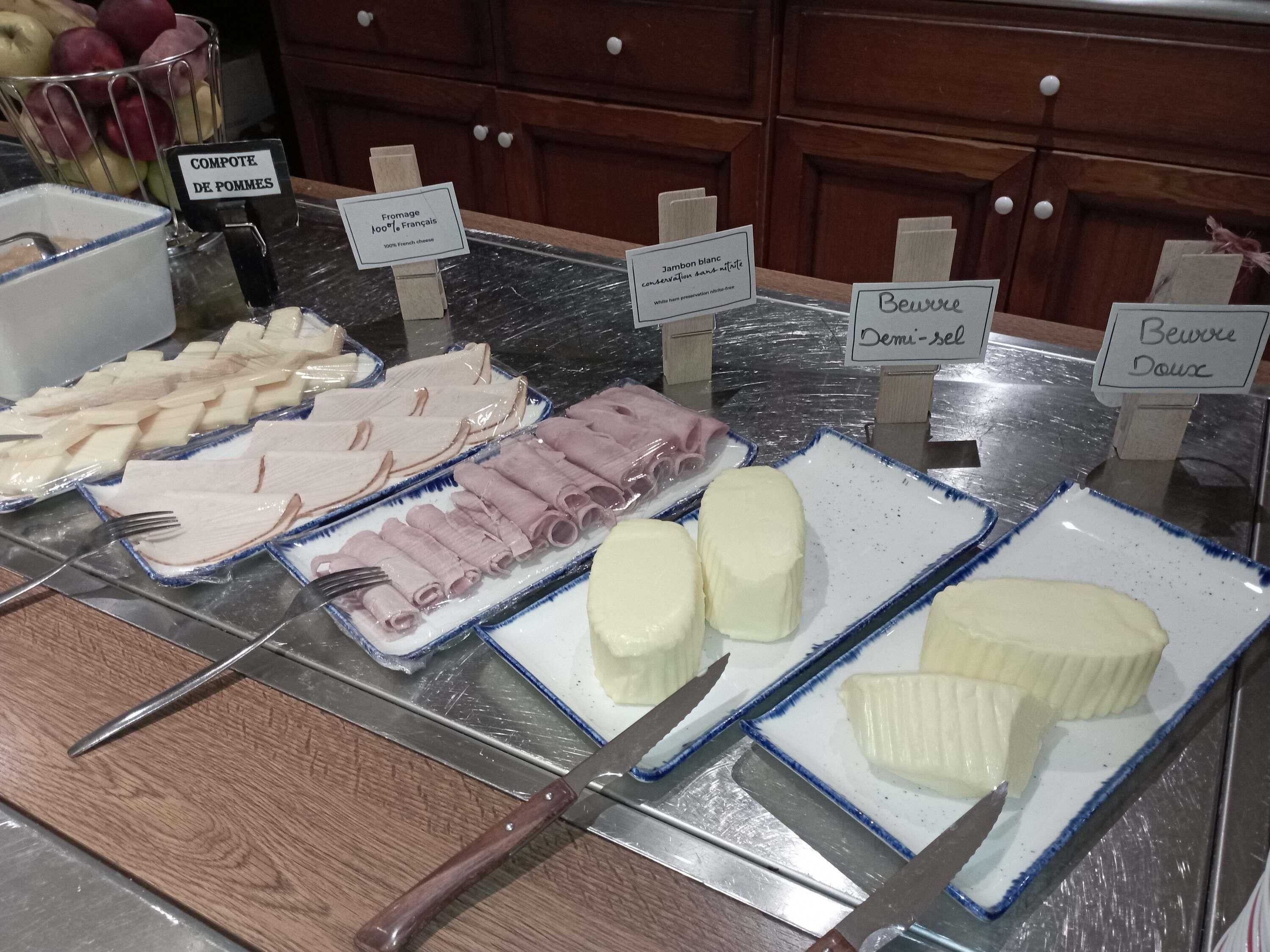 A buffet with various food items including apples, French cheese, and different types of meat.