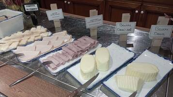 A buffet with various food items including apples, French cheese, and different types of meat.