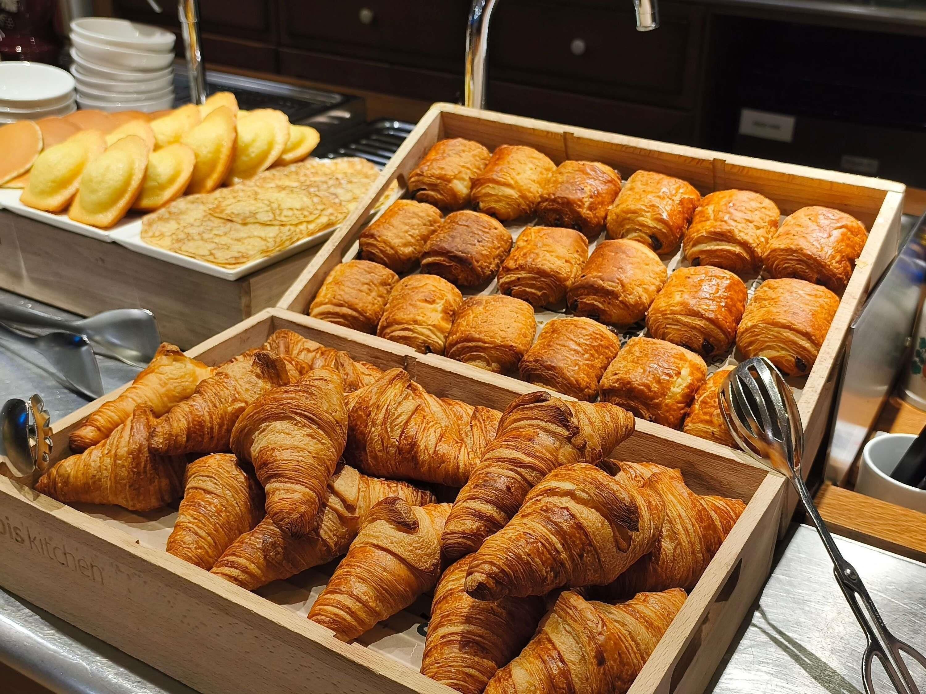 Een buffet met diverse gebakken producten, waaronder croissants en gebak.