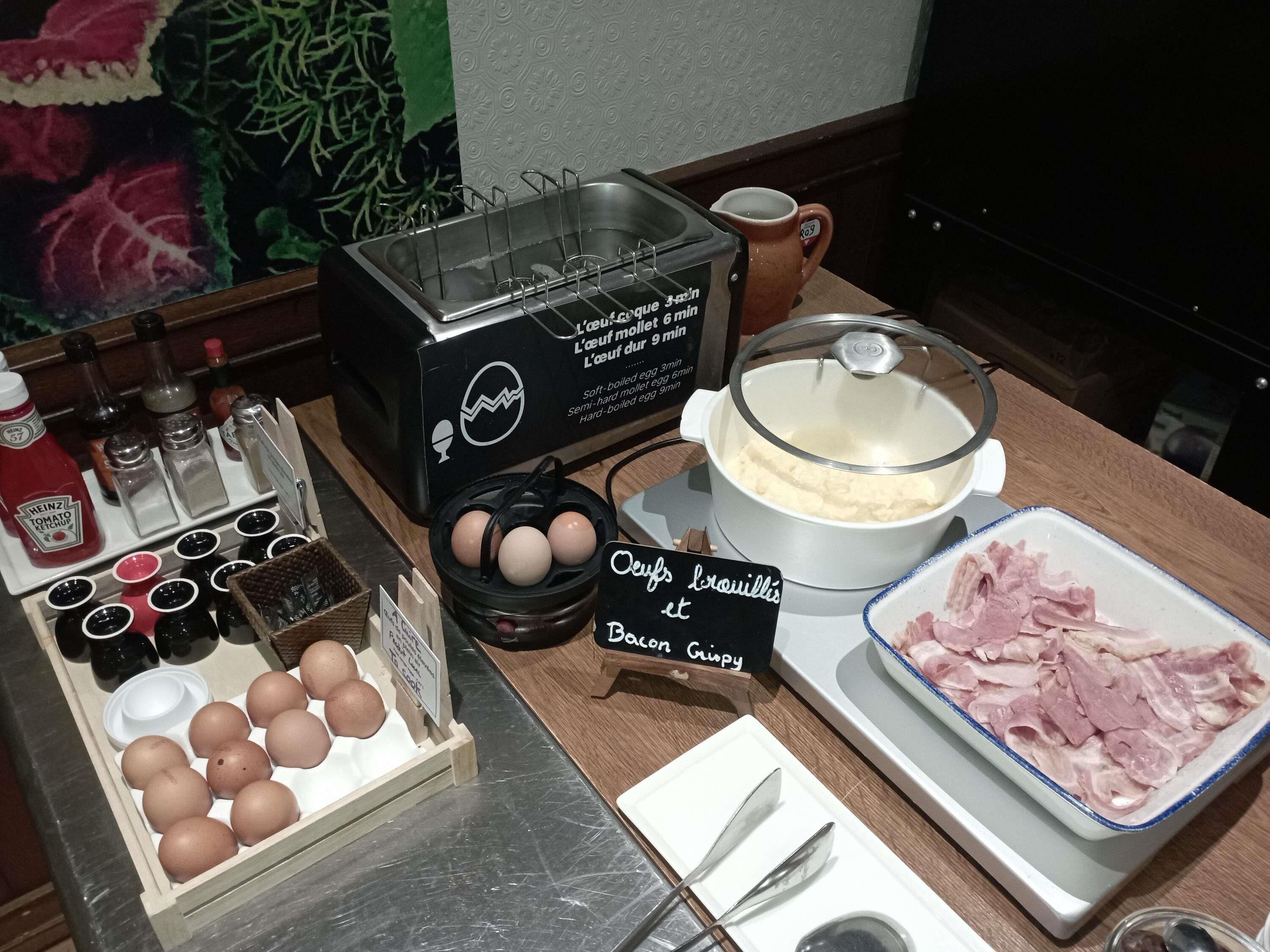 Un bufé de desayuno con huevos, tocino y salsas.