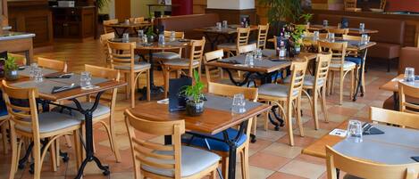 A restaurant with wooden tables and chairs, a bar area, and a television screen.