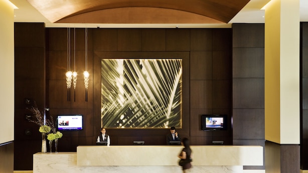 A modern reception area with a marble counter, two monitors, and a large abstract wall art piece.
