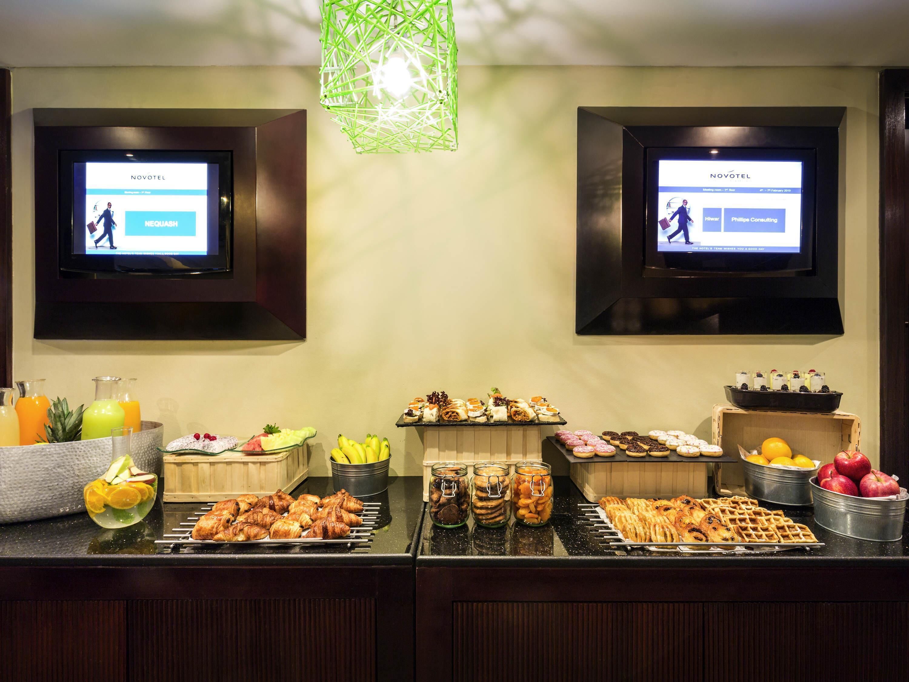 A buffet with various food items and two screens displaying hotel information.