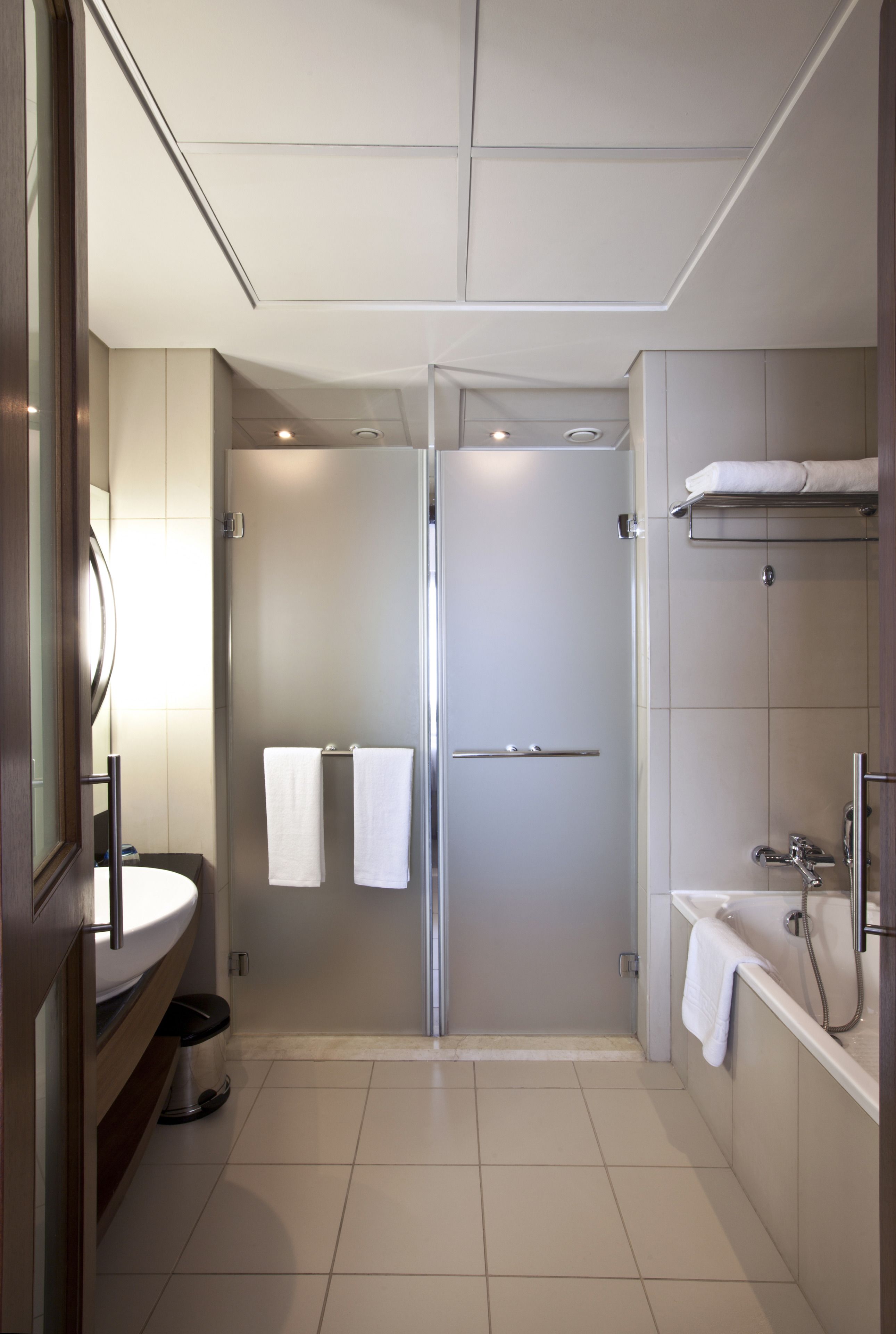 A modern bathroom with a glass-enclosed shower, a sink, and a bathtub.
