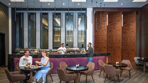 A modern bar area with a counter, bar stools, and a seating area with round tables and chairs.