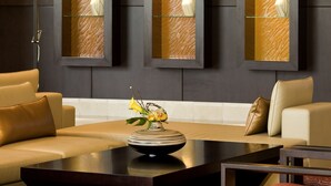 A modern living room with a dark-toned sofa, a coffee table, and a patterned wall unit with shelves.
