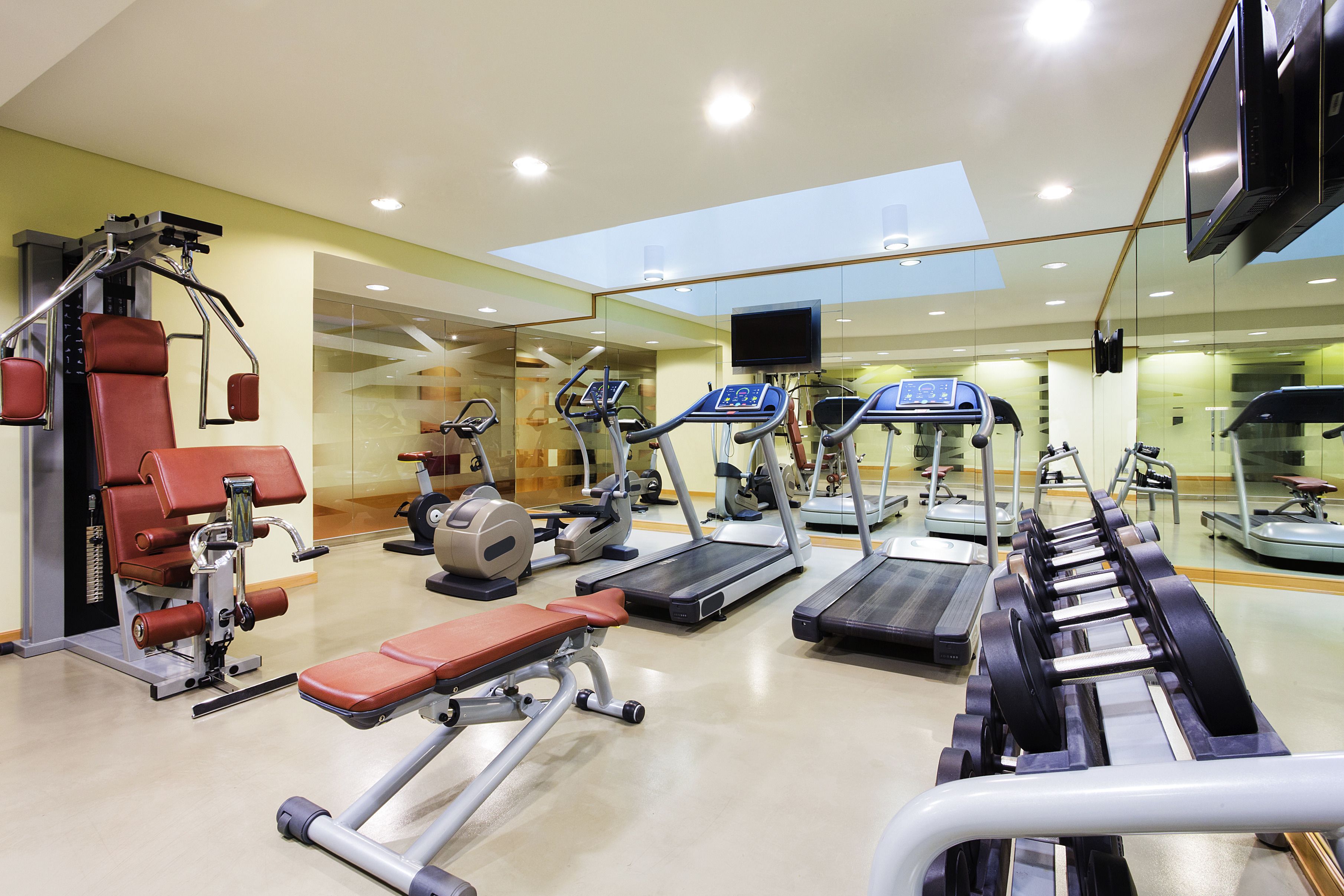Un gimnasio con diversos equipos de ejercicio, incluyendo cintas de correr, bicicletas estáticas y máquinas de pesas.