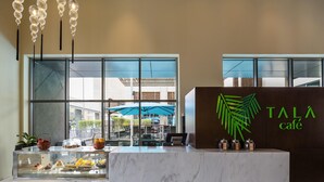 A reception area with a marble counter, a glass display case with desserts, and a sign reading "TALÁ café".