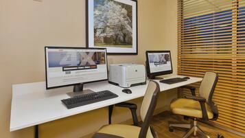 A business center with two desktop computers, a printer, and a framed picture on the wall.