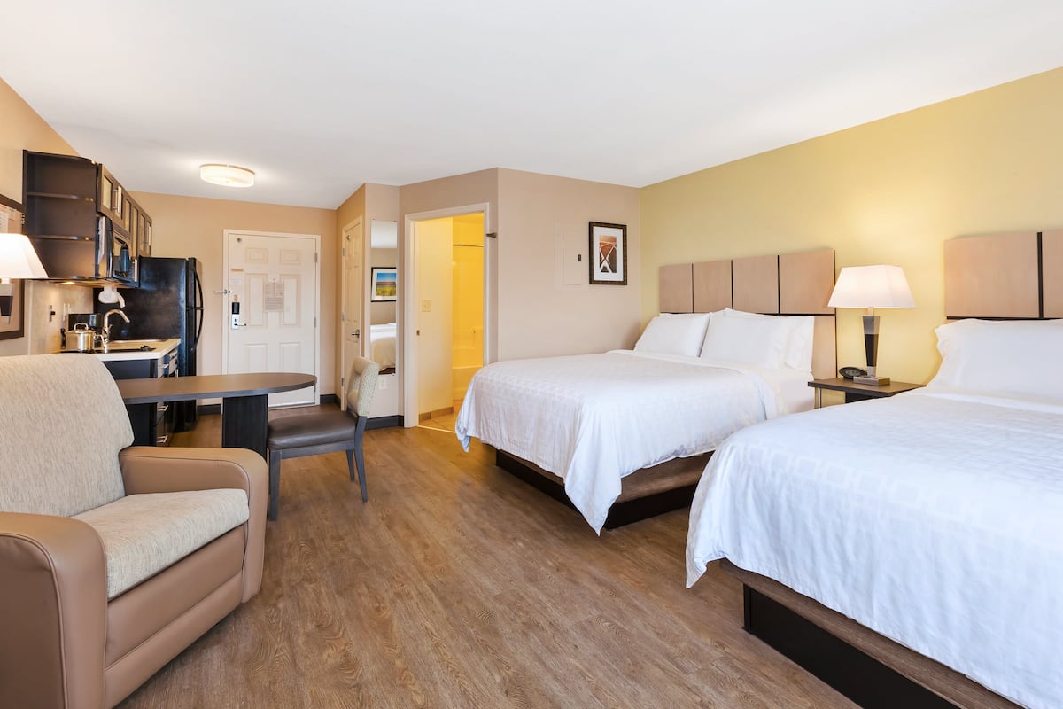 Une chambre d’hôtel avec deux lits, un canapé, une petite table et une kitchenette.