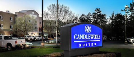 A hotel sign with the name 'CANDLEWOOD SUITES' and a building in the background.