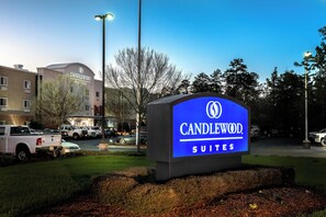Un letrero de hotel con el nombre 'CANDLEWOOD SUITES' y un edificio al fondo.