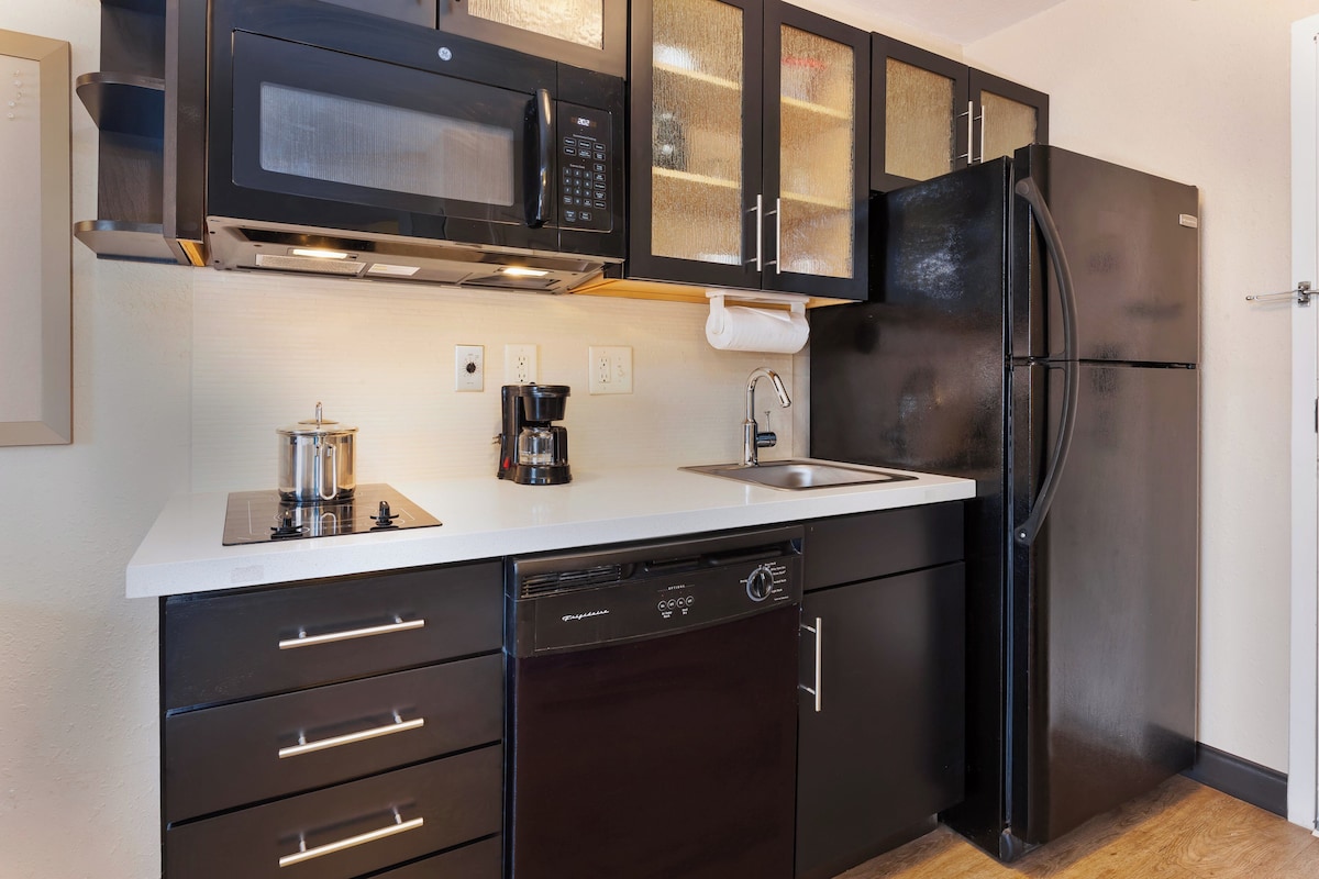 A compact kitchen with a dishwasher, a coffee maker, a microwave, and a refrigerator.