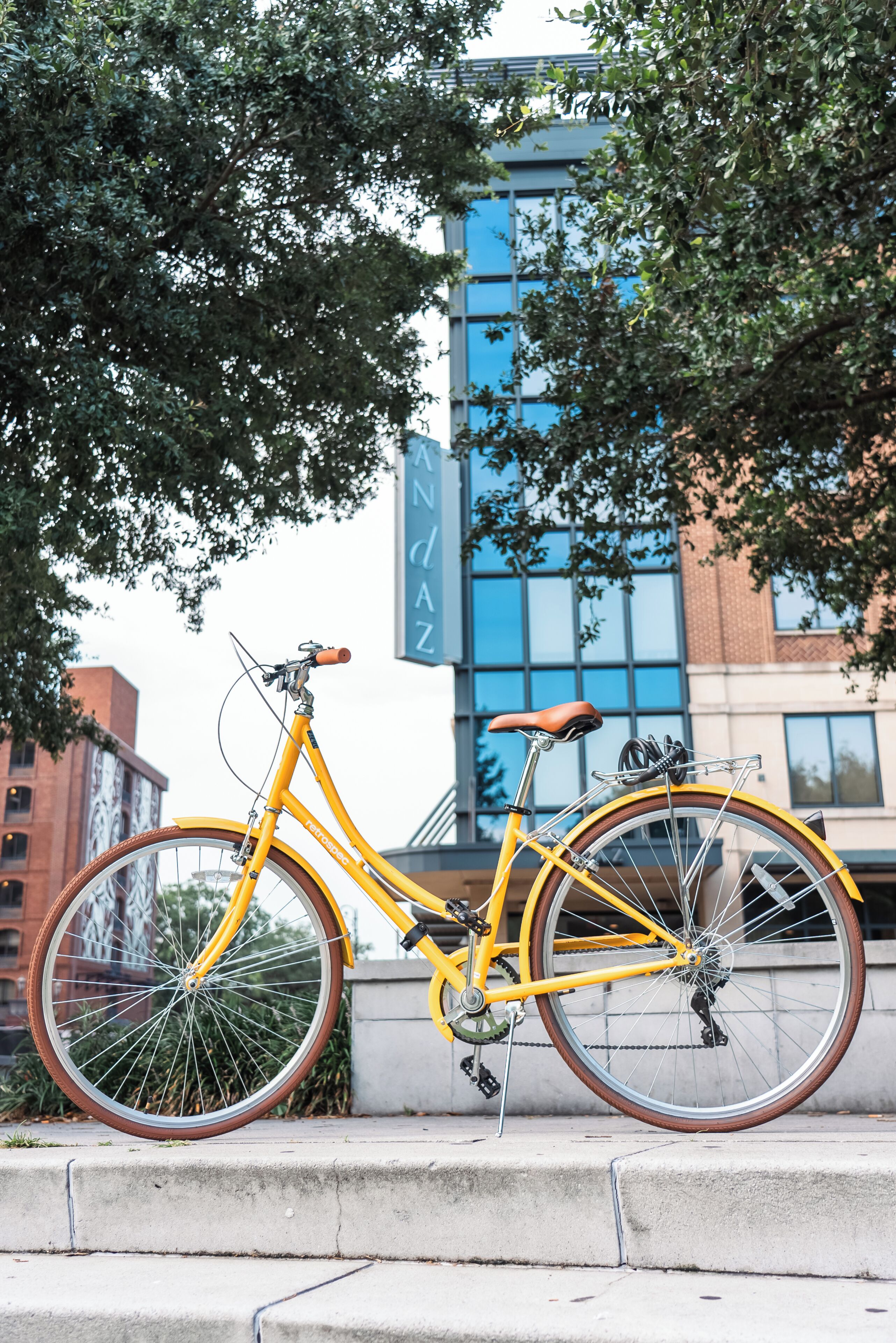 Un vélo jaune est garé sur un trottoir, avec un bâtiment en arrière-plan.