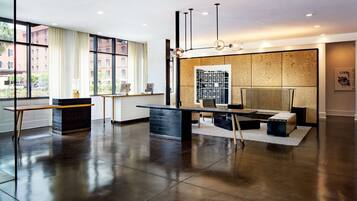 A modern hotel lobby with a reception desk, seating area, and large windows offering a view of the cityscape.