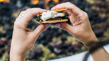 Una persona sosteniendo un postre, con un fuego de fondo.
