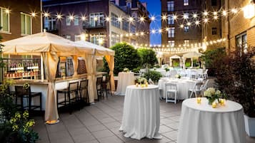 An outdoor patio with round tables, white canopies, and string lights.