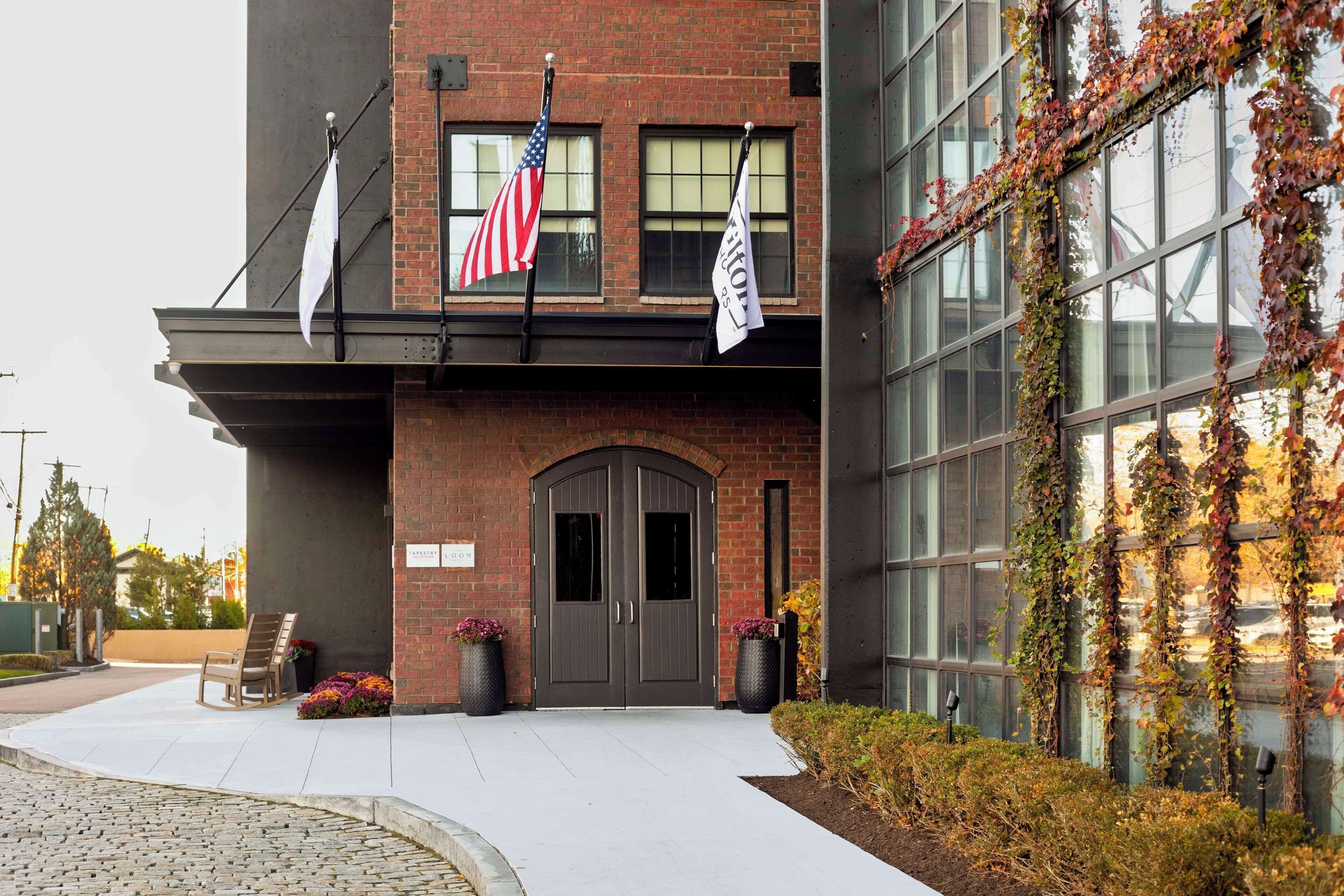 A building with a brick facade, two large double doors, and a flagpole with flags.