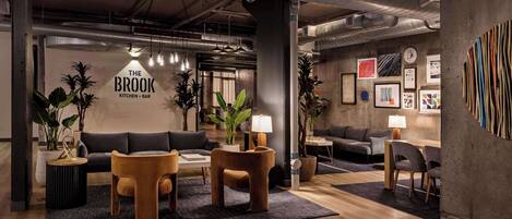A modern interior with a kitchen and bar area, featuring exposed ductwork, wooden flooring, and contemporary furniture.
