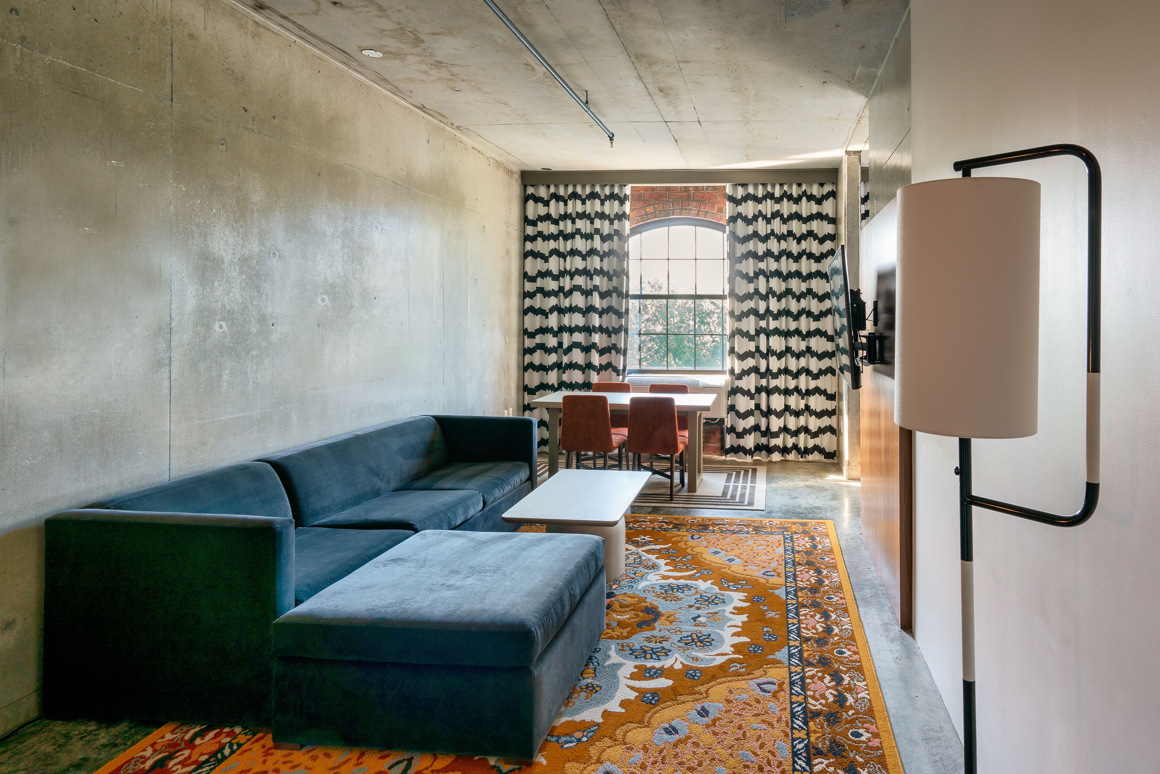 A modern room with a sectional sofa, a small table, and a patterned rug.