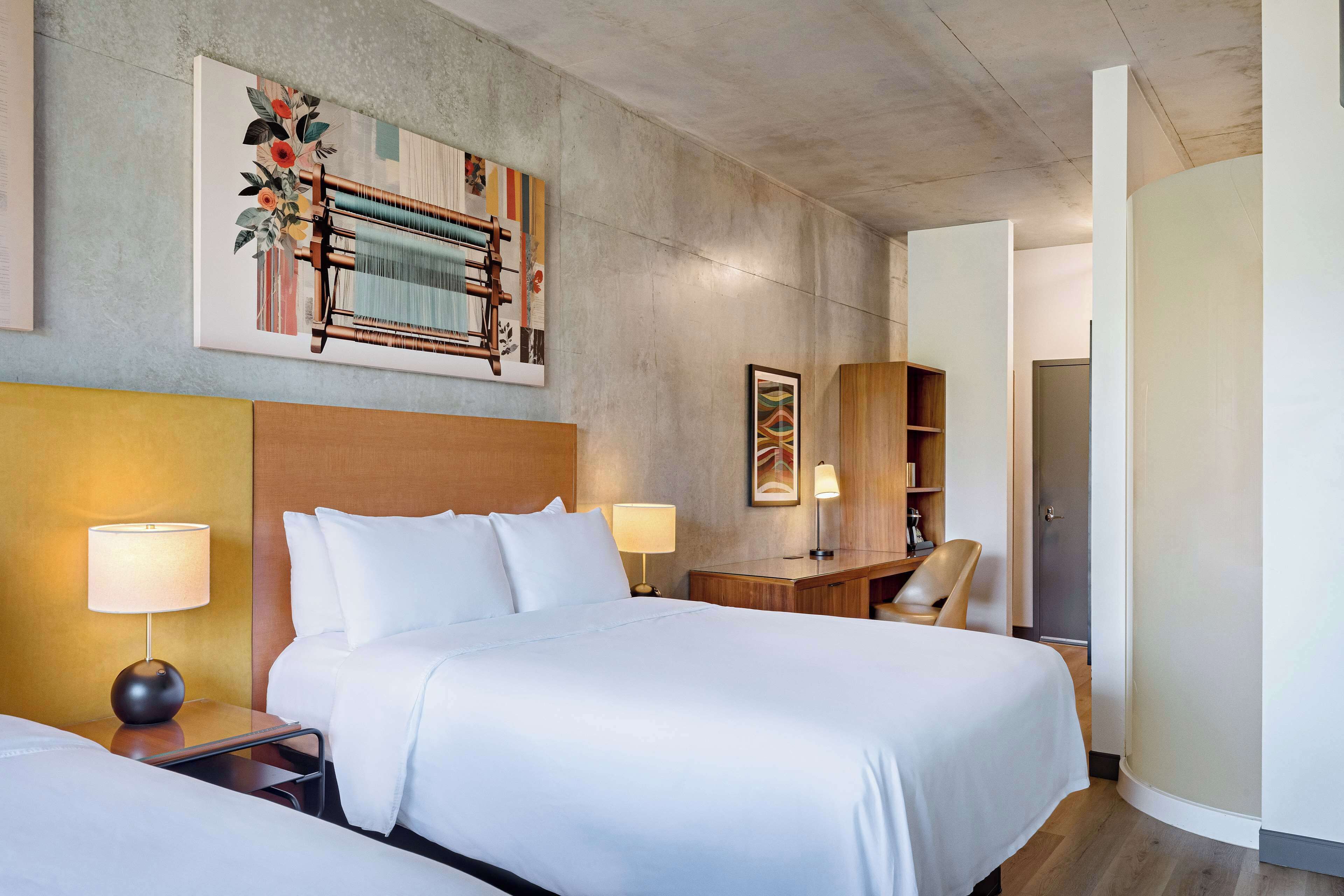 Een hotelkamer met een groot bed, twee nachtkastjes met lampen, een houten bureau en een stoel.