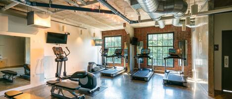 A gym with treadmills, elliptical machines, and weight benches.