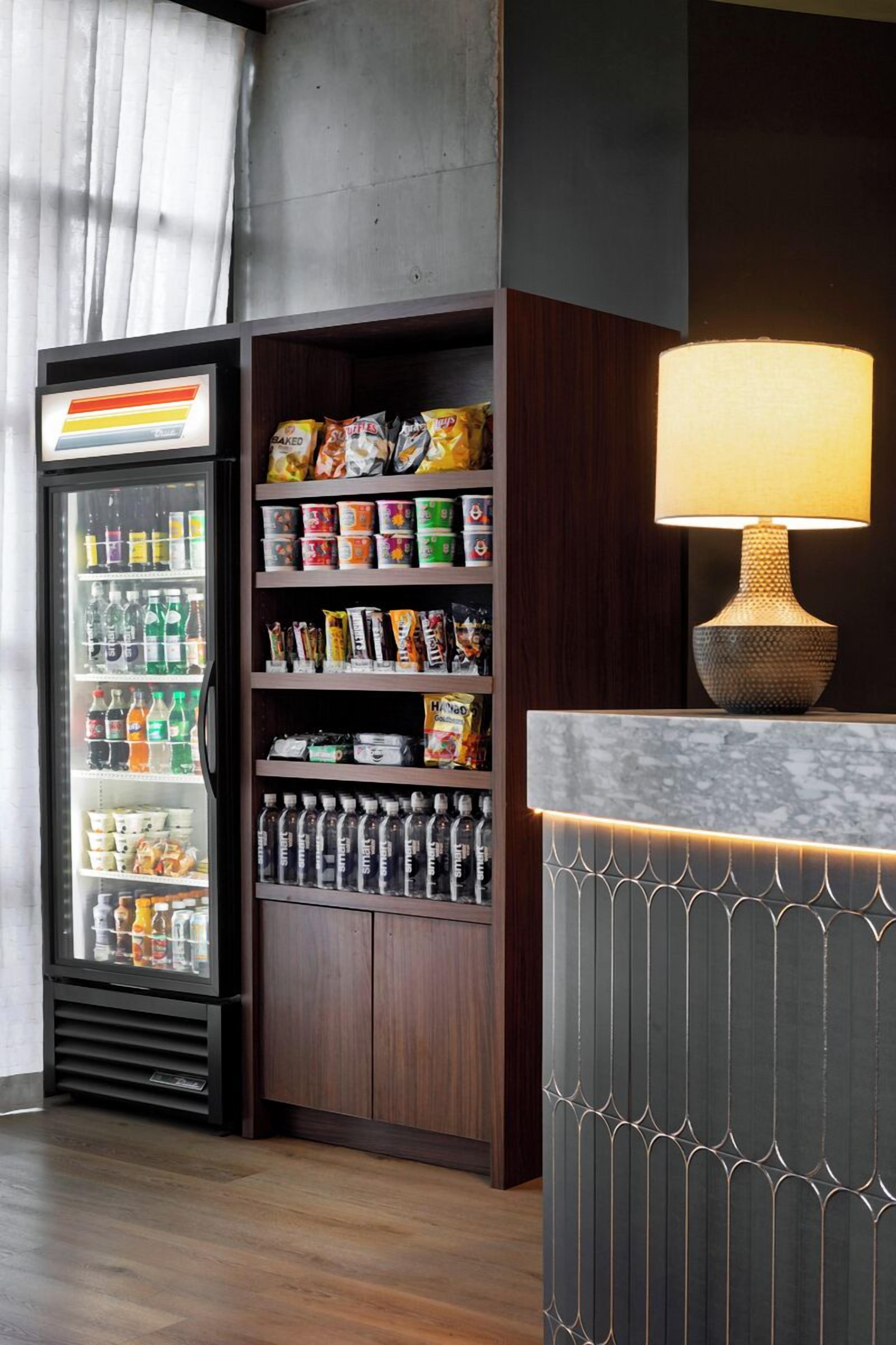 Ein Hotel-Rezeptionsbereich mit einer Minibar, einem mit Getränken gefüllten Kühlschrank und einer Lampe auf einer Theke.
