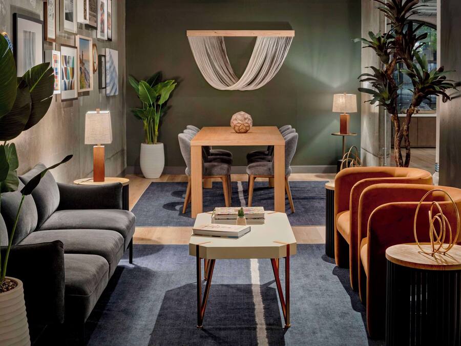 Una sala de estar moderna con un sofá, una mesa de centro, una mesa de comedor con sillas y una planta.