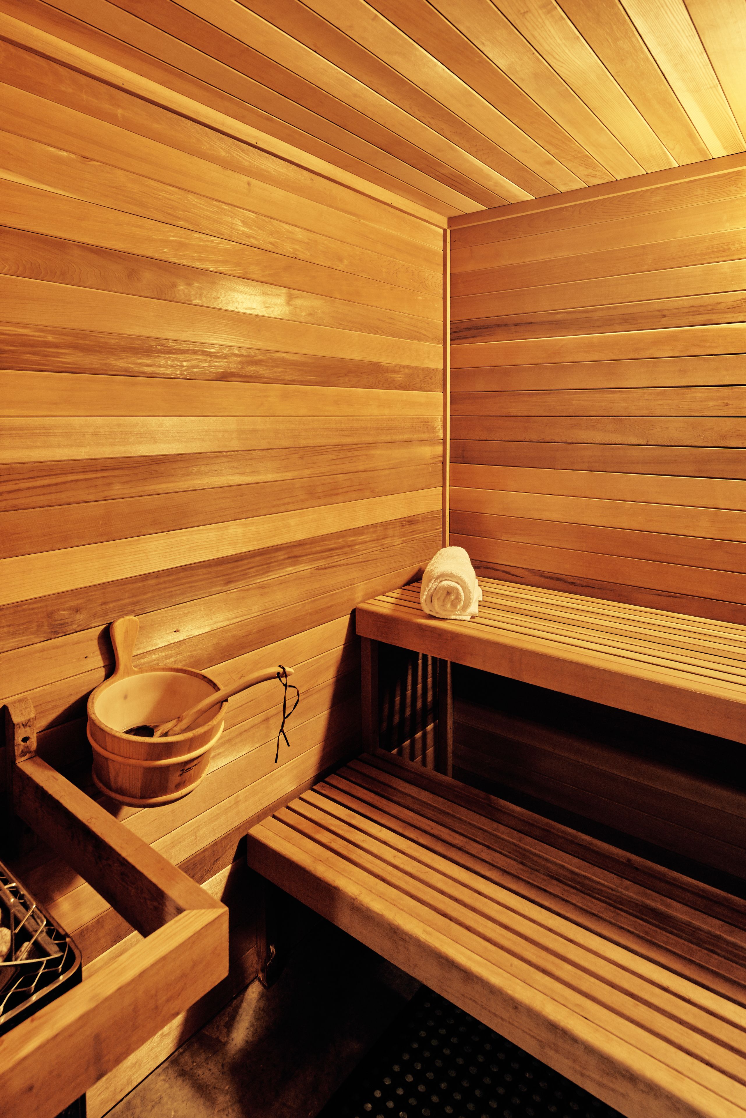 A sauna with wooden benches and a wooden bowl.