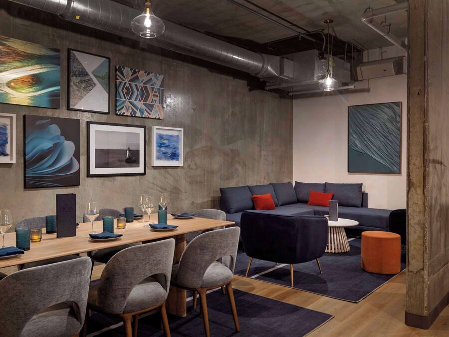 Un interior moderno con zona de comedor, un sofá y obras de arte en las paredes.
