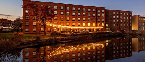 A large brick building with multiple windows and a reflection in the water.
