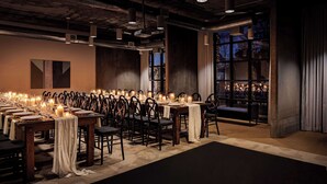 A long dining table set with candles and chairs, with a view of the outside through a large window. - The Loom Hotel, Tapestry Collection by Hilton (Warwick)