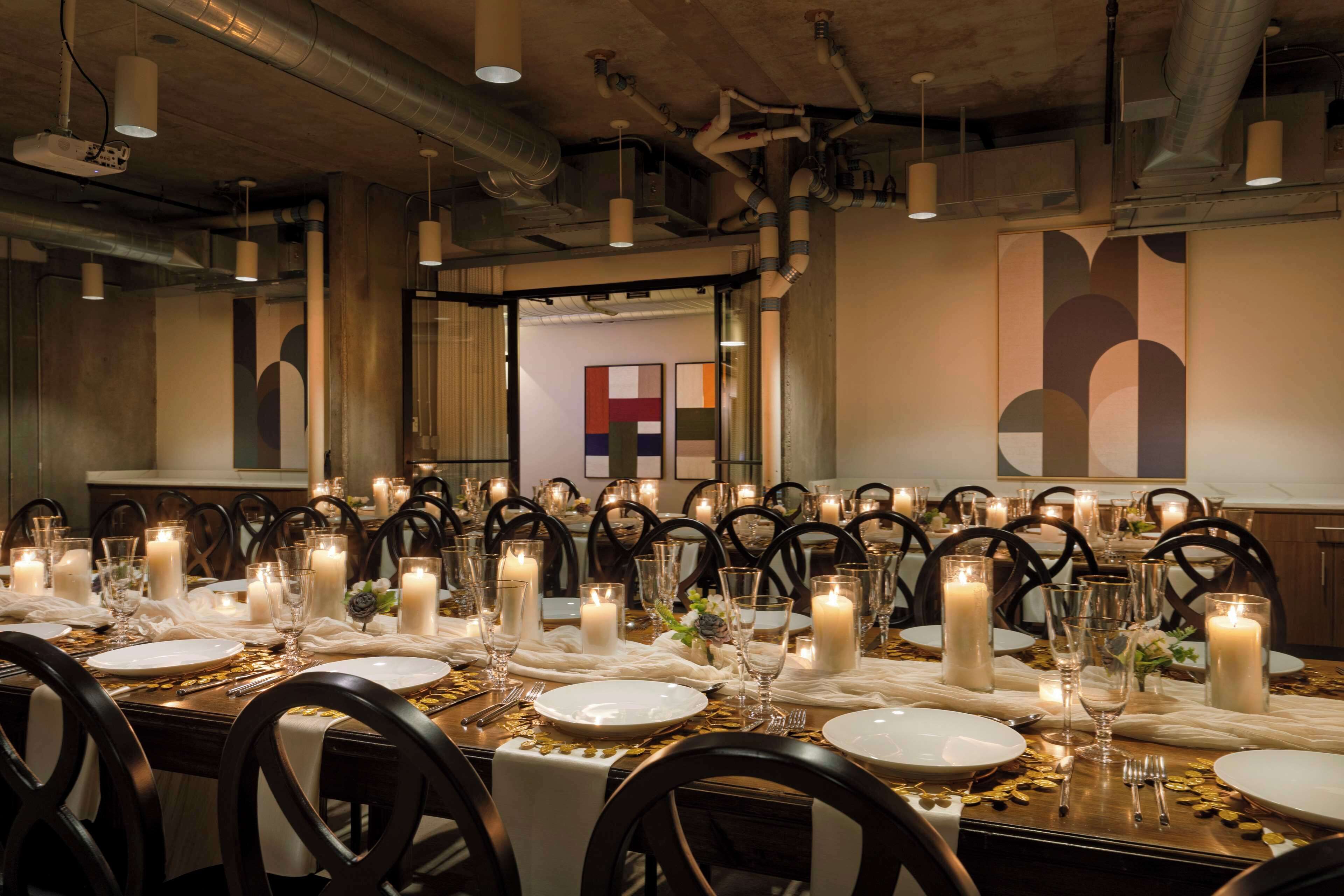 Un comedor formal con varias mesas dispuestas para una comida, cada una con velas, platos y cubiertos.
