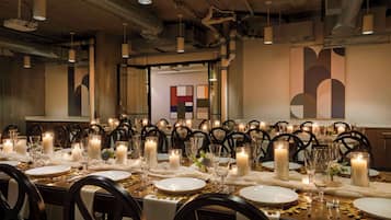 Un comedor formal con varias mesas dispuestas para una comida, cada una con velas, platos y cubiertos.